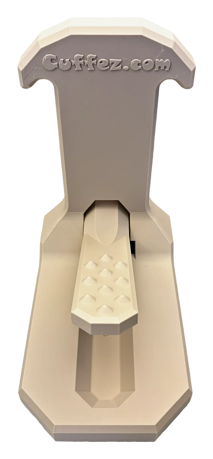 Cuffez in Sand: a flat base, an upright post with a T-shaped head, and a spiked pedal on a pivoting arm.